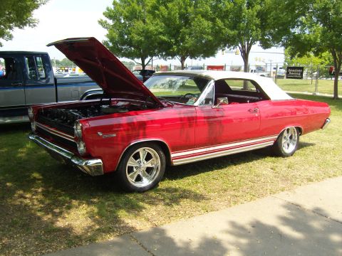2007 Ford Mustang - A red 1967 Mercury Cougar convertible is displayed with its hood open, parked beside a pickup truck.