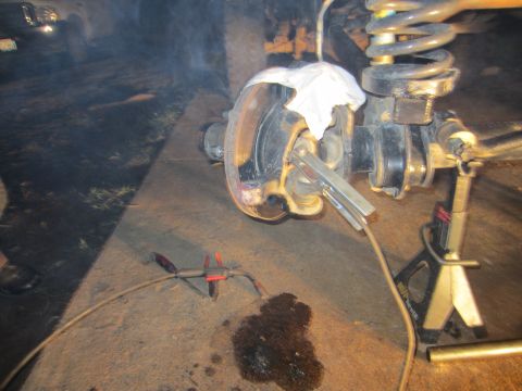 1992 Ford Bronco - Welding is being performed on a vehicle's suspension component, with a white cloth covering part of the assembly.