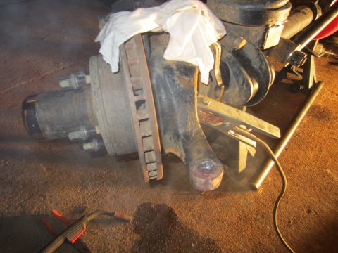 1992 Ford Bronco - Close-up of a Ford Bronco steering knuckle, brake rotor, and hub assembly, possibly undergoing repair.