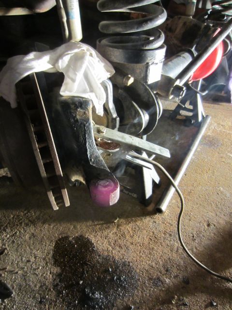 1992 Ford Bronco - Close-up view of automotive suspension components, including a brake rotor and coil spring, on a workshop floor.