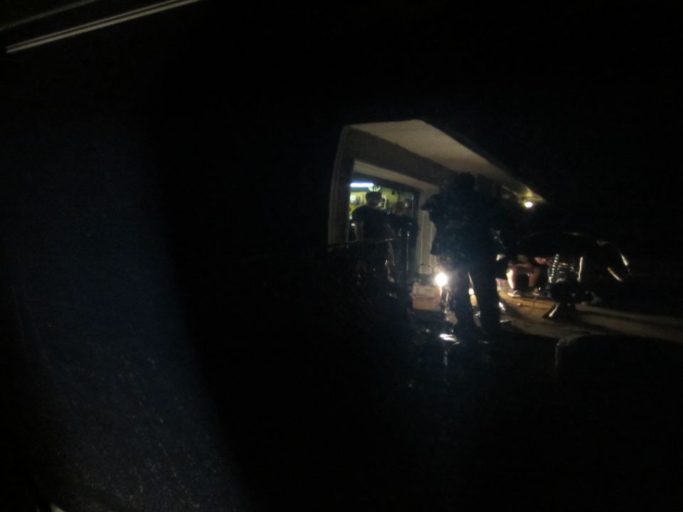 People working on a vehicle at night under a light