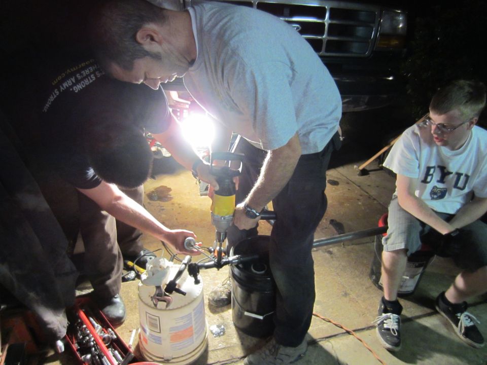 Front grille of a 1990s Ford truck, with people working on something below it