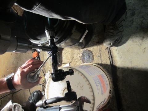1992 Ford Bronco - Mechanic works on a vehicle's steering linkage, with tools and a bucket nearby.