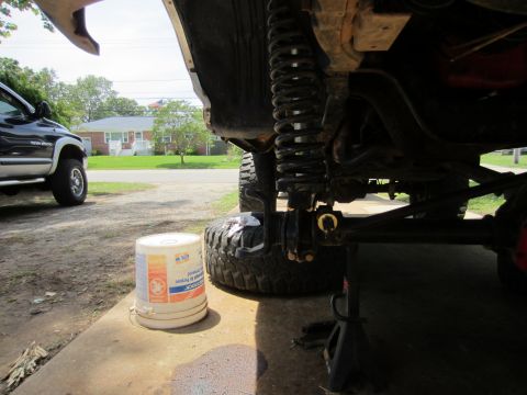 1992 Ford Bronco - Close-up view of the undercarriage and suspension of a lifted vehicle, with another truck in the background.