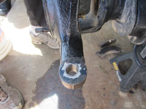 1992 Ford Bronco - A close-up view of a vehicle's steering knuckle, with brake pads and a jack stand visible in the background.