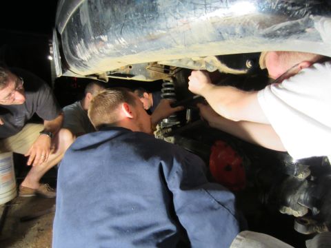 1992 Ford Bronco - A group of people are focused on the suspension components of a vehicle, likely during a repair or modification.