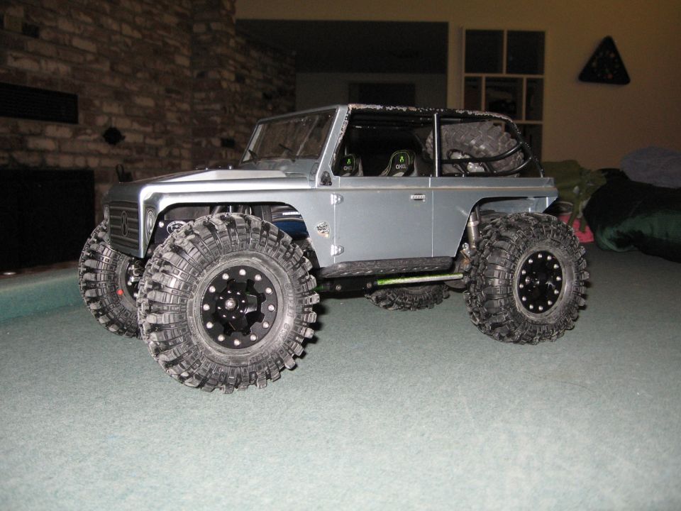 Silver RC off-road vehicle with oversized tires and roll cage