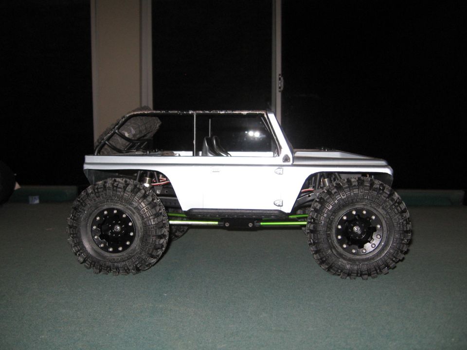White remote control rock crawler with large off-road tires and green suspension components