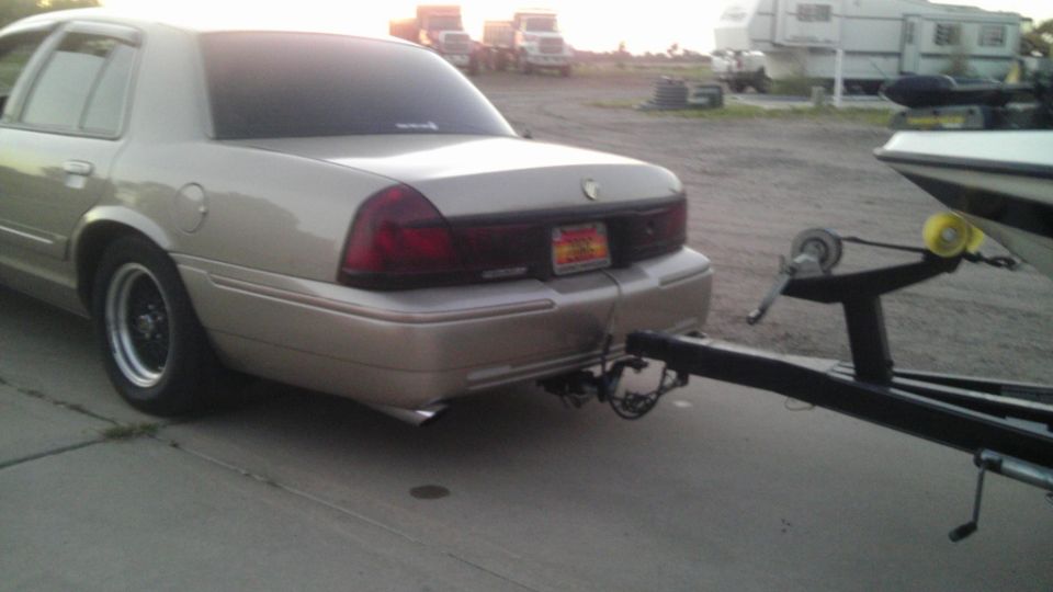 Rear view of a gold Mercury Grand Marquis towing a boat trailer
