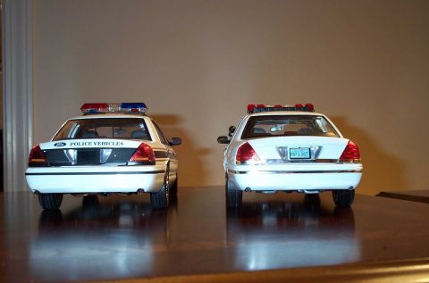 1998 Ford Crown Victoria - Two model police cars, likely Ford Crown Victorias, displayed from the rear.