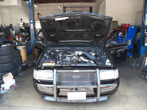 2003 Ford Crown Victoria - Head-on shot of a black Crown Victoria in a garage, hood up showing engine and front-mount intercooler.