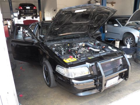 2003 Ford Crown Victoria - Crown Victoria parked in a garage bay, hood and door open with intercooler behind the push bar.