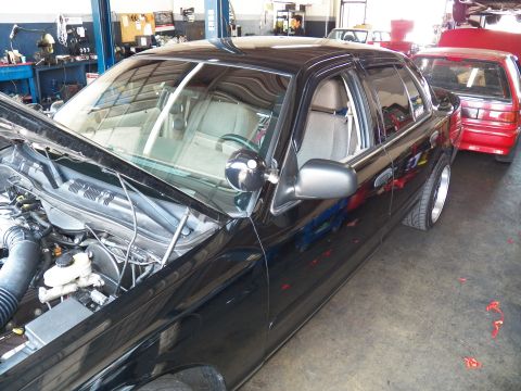 2003 Ford Crown Victoria - Driver-side view of a Crown Victoria in a garage, hood propped open and door-mounted spotlight.