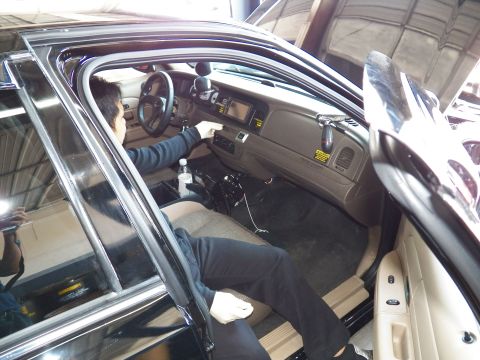 2003 Ford Crown Victoria - Interior of a Crown Victoria with a person seated at the wheel beside a tan dash and floor shifter.