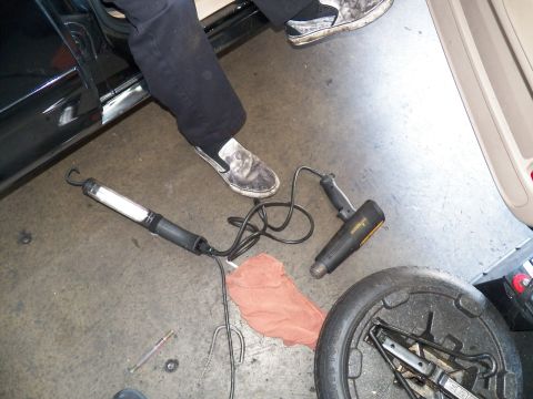 2003 Ford Crown Victoria - Technician legs in the doorway with a corded work lamp and tools on the garage floor