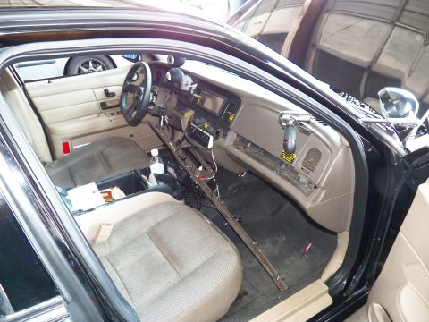 2003 Ford Crown Victoria - Driver cabin of a sedan mid-service showing center display and detached sill panel