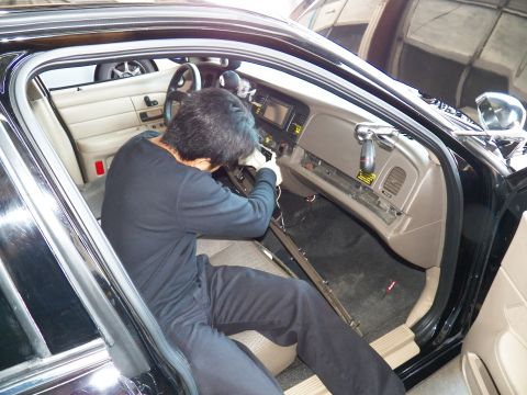 2003 Ford Crown Victoria - Worker leans into the dash of a Crown Victoria with beige interior and exposed sill