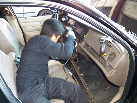 2003 Ford Crown Victoria - Worker services the center stack of a Crown Victoria with wiring and sill exposed
