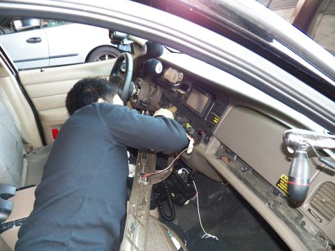 2003 Ford Crown Victoria - Center stack display and column under a tan dash as a technician routes wiring inside the car.