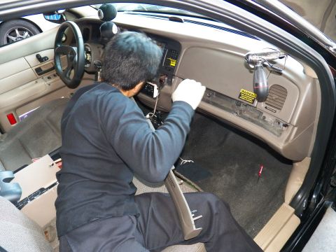 2003 Ford Crown Victoria - Man in dark clothing reaches under the tan dash near the glovebox during an interior install.