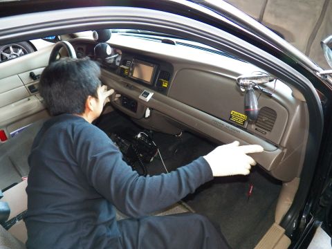 2003 Ford Crown Victoria - Technician spreads gloved hands across the lower tan dash while wiring the center stack.