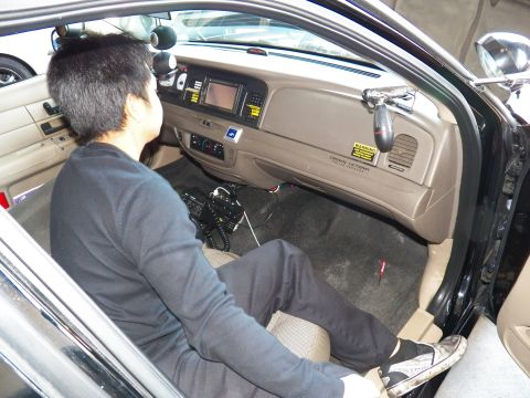 2003 Ford Crown Victoria - Man sits in the passenger footwell routing wires under a tan dash with center display.