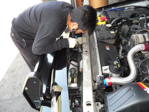 2003 Ford Crown Victoria - Worker reaches into a V8 engine bay fitting a metal tube near a K&N air intake.