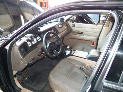 2003 Ford Crown Victoria - Driver side of a tan interior fitted with a sport wheel, extra gauges and cloth bucket seats.