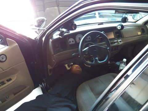 2003 Ford Crown Victoria - Dashboard, instrument cluster and tan trim of a sedan with someone lying across the front seats