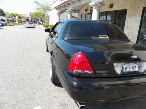 2003 Ford Crown Victoria - Rear of a black full-size Ford sedan with EVTL VTC California plate and single exhaust tip in a lot