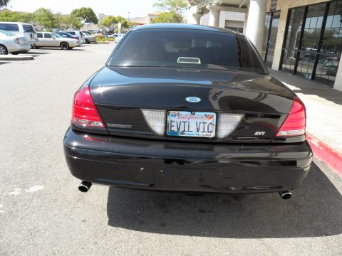 2003 Ford Crown Victoria - Rear of a black Ford sedan badged SVT showing EVL VIC plate and chrome exhaust tips in a parking lot