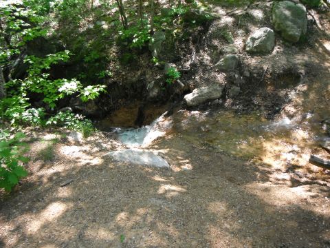 1988 Ford Bronco - Water flows through a natural landscape with trees and rocks.