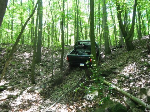 1988 Ford Bronco - A black pickup truck navigates a rocky, wooded trail.