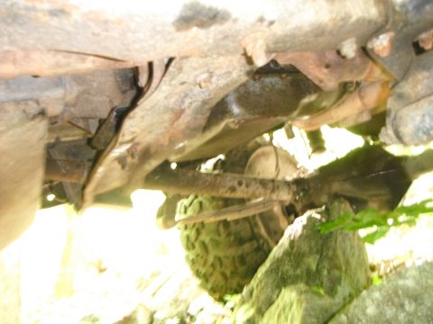 1988 Ford Bronco - Close-up of the undercarriage of a vehicle, showing mechanical parts and off-road terrain.