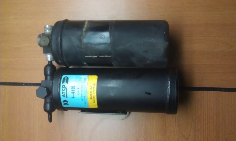 Two black cylindrical automotive parts stacked, one with a blue and yellow ATCO label