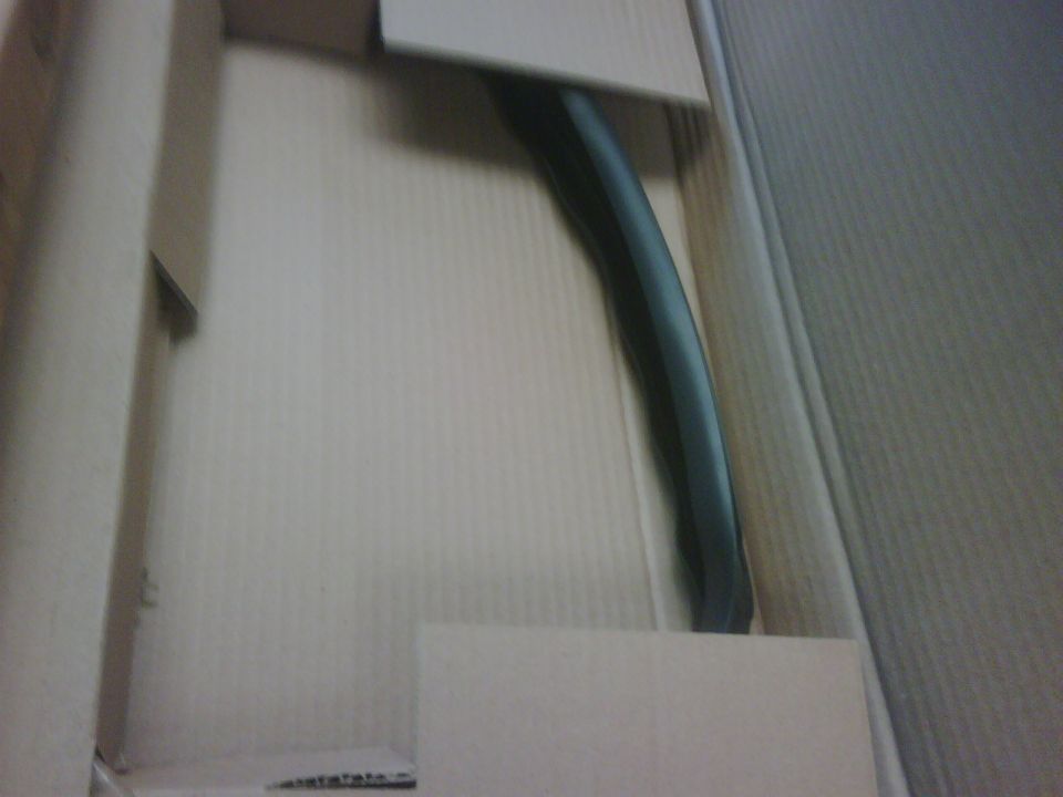 Black curved car part inside a cardboard box
