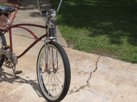1994 Ford Bronco - A red cruiser bicycle is parked on a concrete path next to a grassy area.