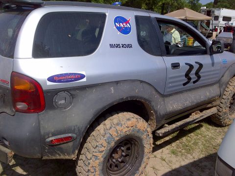 1999 Isuzu Vehicross - This modified SUV features off-road tires and decals, suggesting it's prepared for rough terrain.