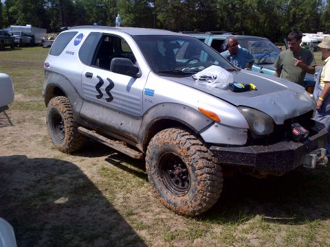 1999 Isuzu Vehicross - Modified 1999 Isuzu Vehicross with off-road tires and racing numbers, seen outdoors with other vehicles and people.