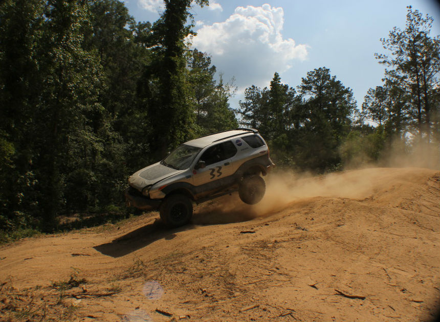 Silver SUV with number 33 on the door driving off-road and kicking up dust