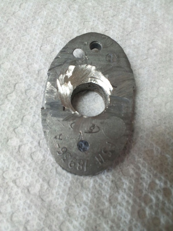 Oval metal part with a central hole, showing machined marks and stamped numbers including '18936'