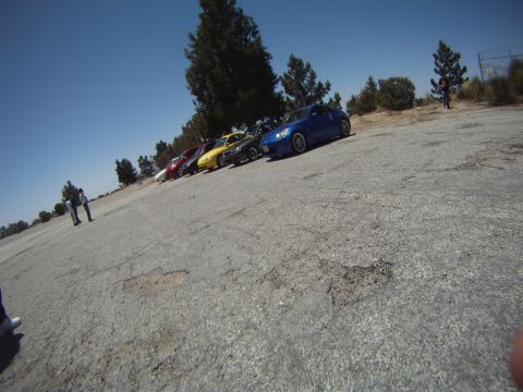 1990 Ford Probe - A line of cars, including a blue sports car, are parked on a sunny day.