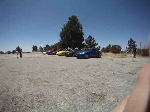 1990 Ford Probe - A line of cars, including a blue coupe, are parked in an outdoor lot under a clear blue sky.