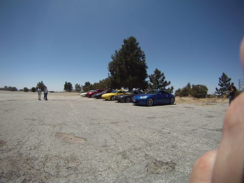 1990 Ford Probe - A group of sports cars are parked in a line on a paved lot under a clear blue sky.