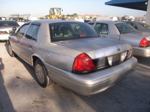 2005 Ford Crown Victoria - A silver Ford Crown Victoria is parked in an outdoor lot, with other vehicles and construction equipment visible.
