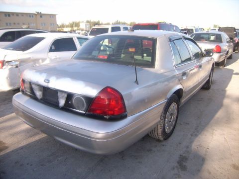 2005 Ford Crown Victoria - Rear 3/4 view of a silver 2005 Ford Crown Victoria parked in an outdoor lot with other vehicles.