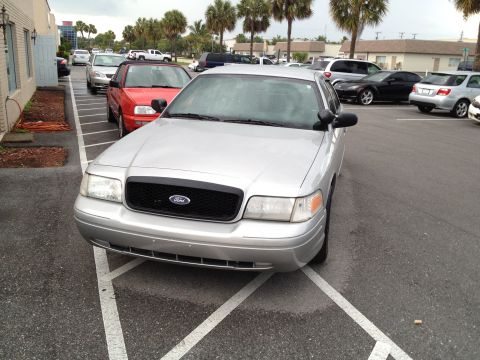 2005 Ford Crown Victoria - A silver Ford Crown Victoria is parked in a lot with other vehicles around it.