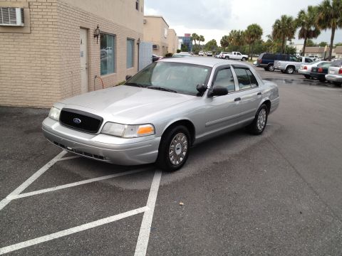 2005 Ford Crown Victoria - A silver 2005 Ford Crown Victoria is parked in a lot with other vehicles in the background.