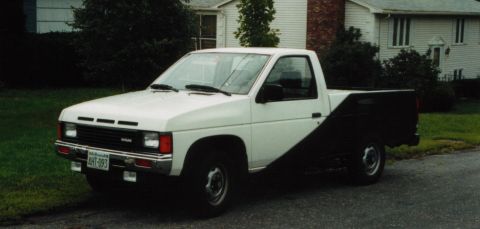 1991 Ford LTD Crown Victoria - A two-tone Nissan pickup truck is parked in front of a house on a cloudy day.