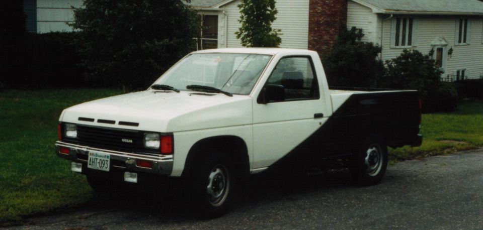 White and black Nissan pickup truck parked on a residential street